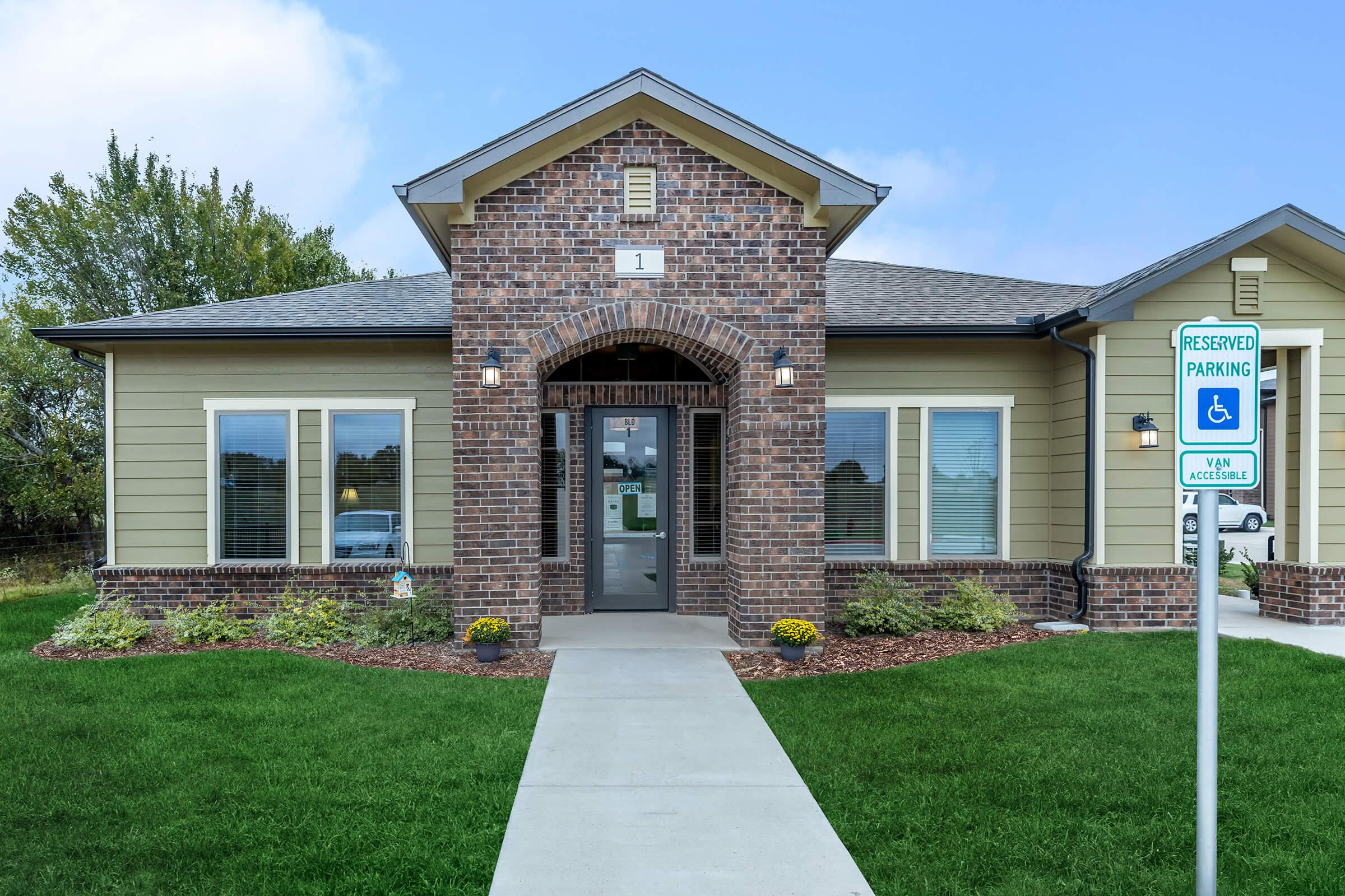 a house with a lawn in front of a brick building