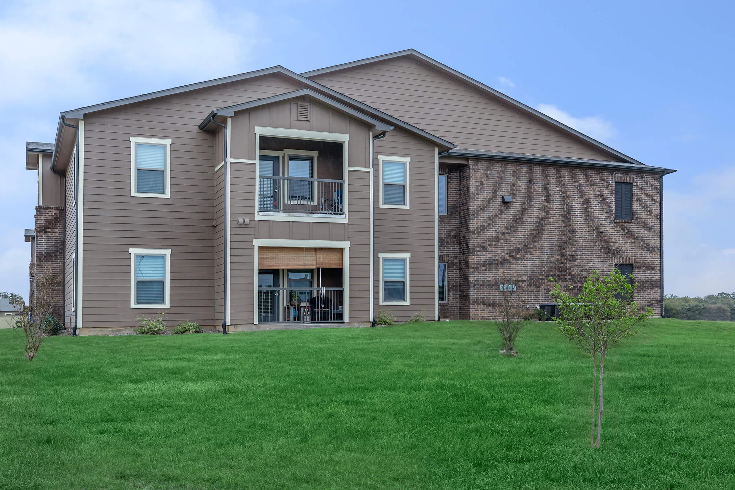 a large brick building with grass in front of a house