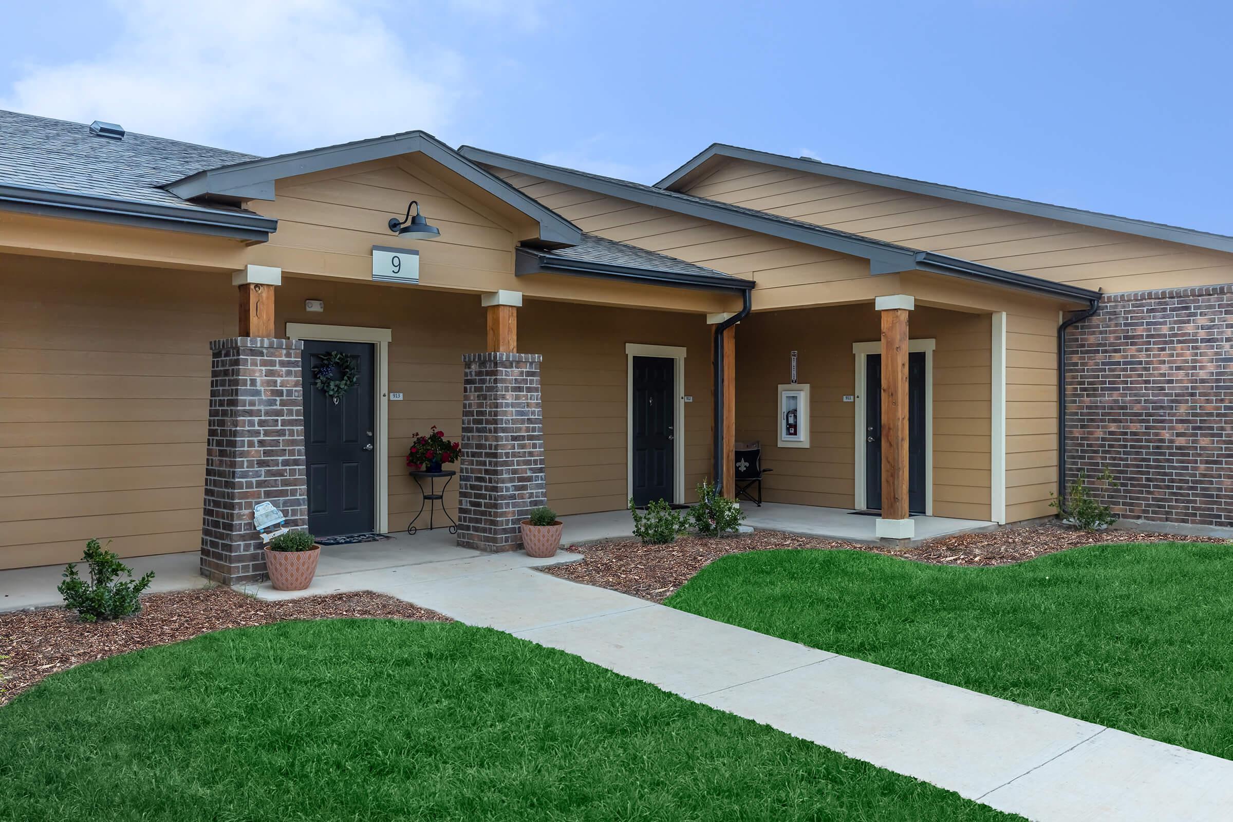 a house with a lawn in front of a brick building