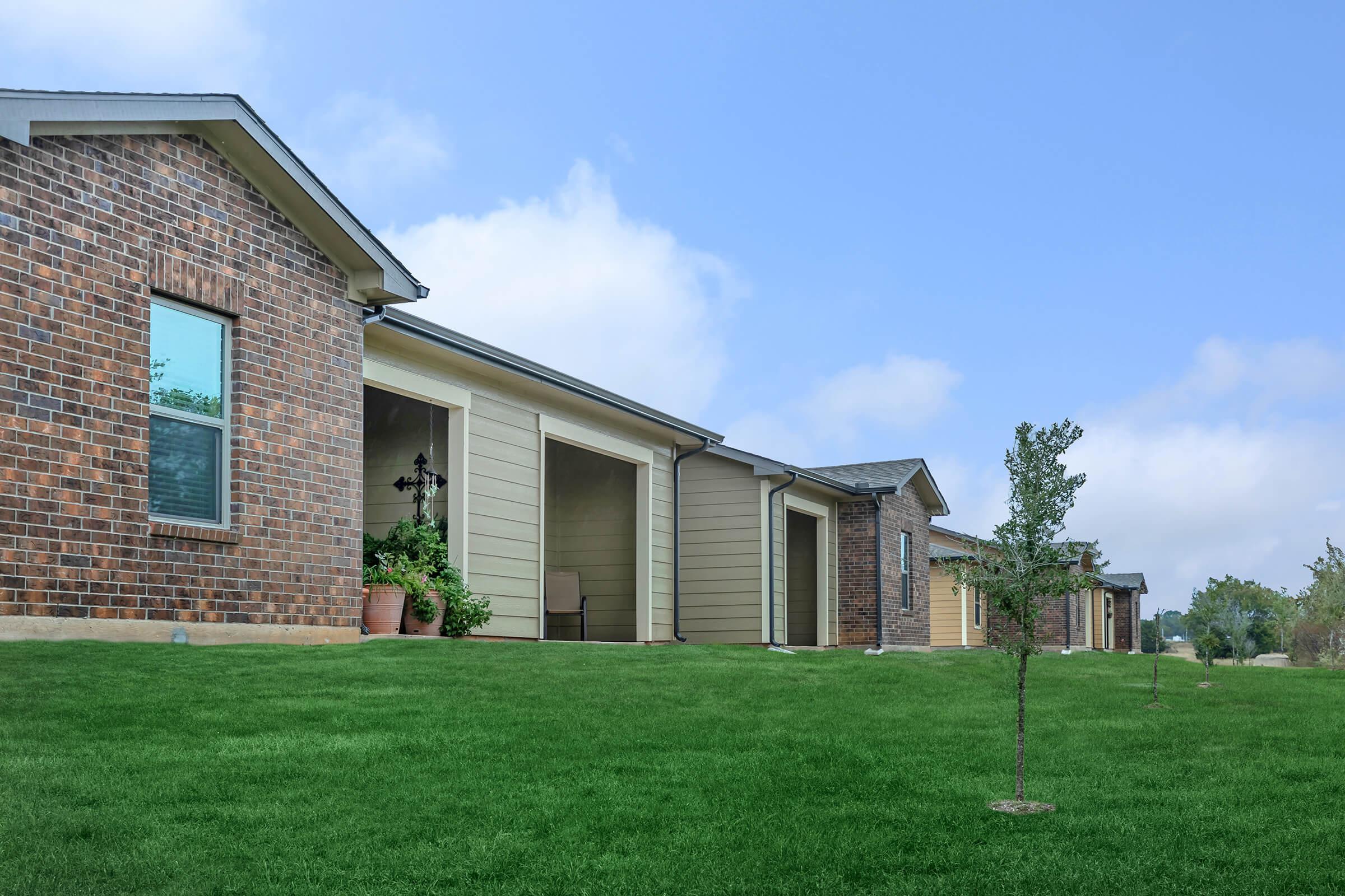 a house with a lawn in front of a brick building