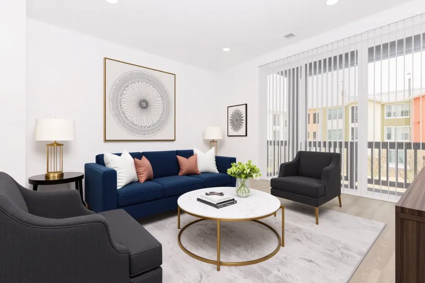 A modern living room featuring a navy blue sofa with decorative pillows, a round coffee table with a book and a small vase of flowers, two dark armchairs, and stylish artwork on the walls. Large windows with vertical blinds allow natural light to fill the space, enhancing the contemporary aesthetic.