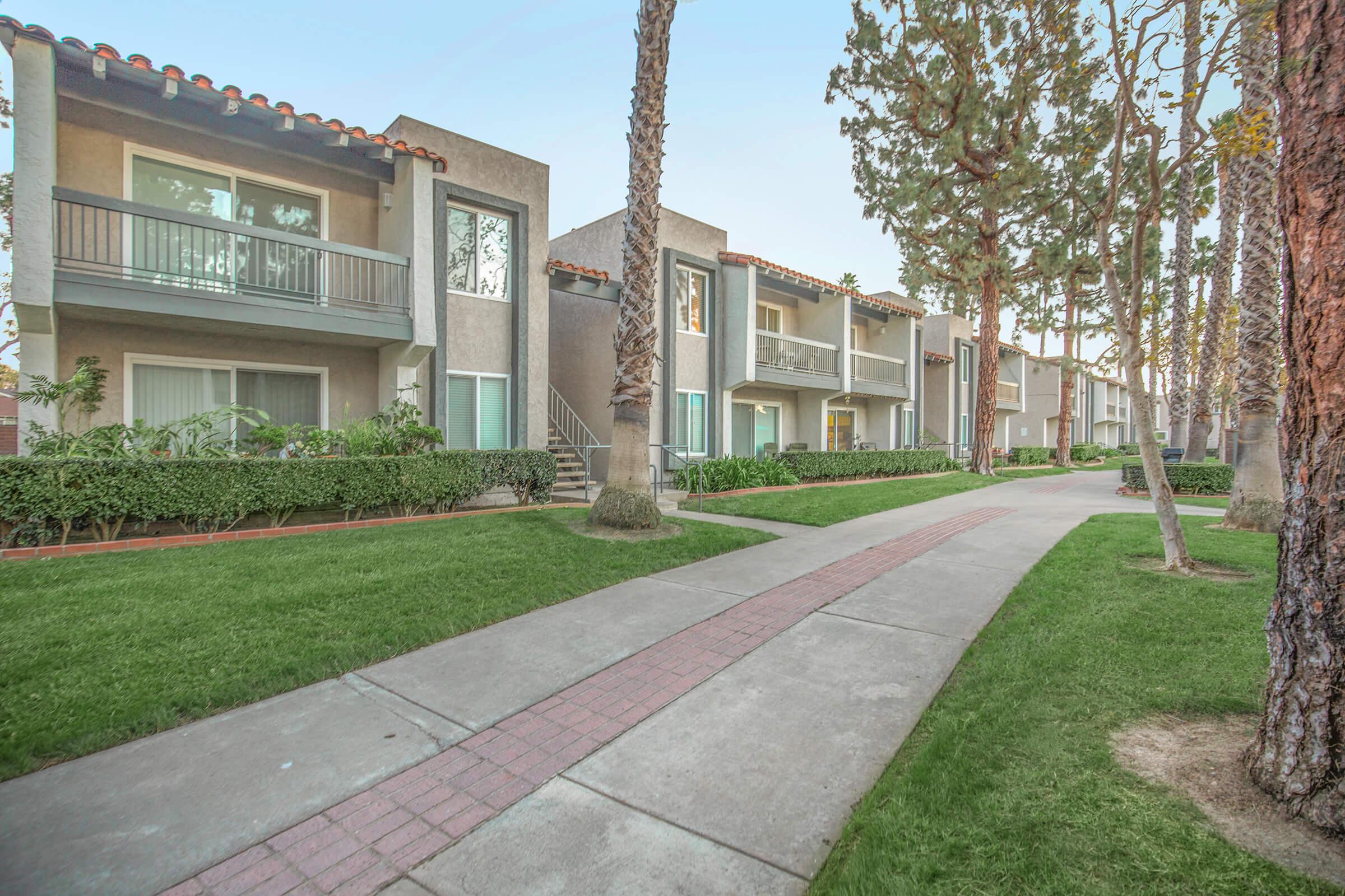 a path with grass in front of a building