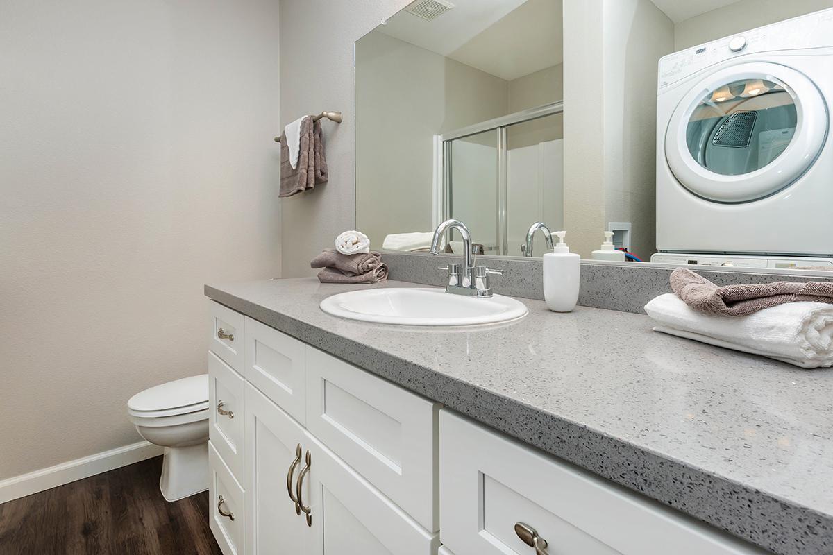 a white sink sitting under a mirror