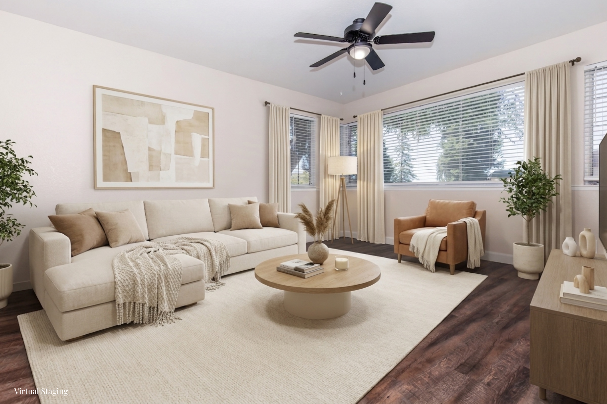A stylish living room featuring a large beige sofa with a throw blanket, an accent chair, and a round coffee table. Natural light streams through window coverings, illuminating a neutral color palette with decorative accents, including a plant and decorative vases. The flooring is dark wood, enhancing the cozy atmosphere.
