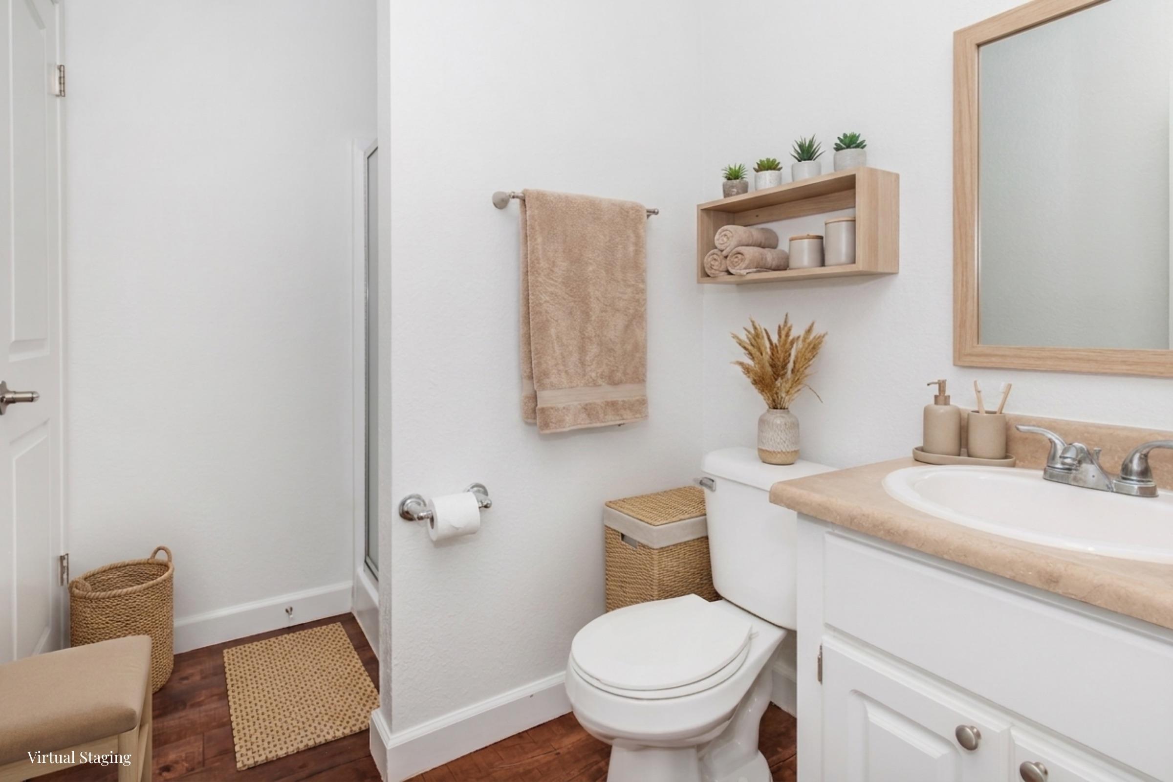 A clean and modern bathroom featuring a white toilet, a sink with a wooden countertop, and a rectangular mirror. Decor includes a wall-mounted shelf with plants, towels, and decorative items, as well as a woven basket and bath mat on the floor. The walls are painted light, enhancing the spacious feel.
