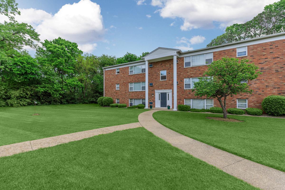 a large brick building with a grassy field