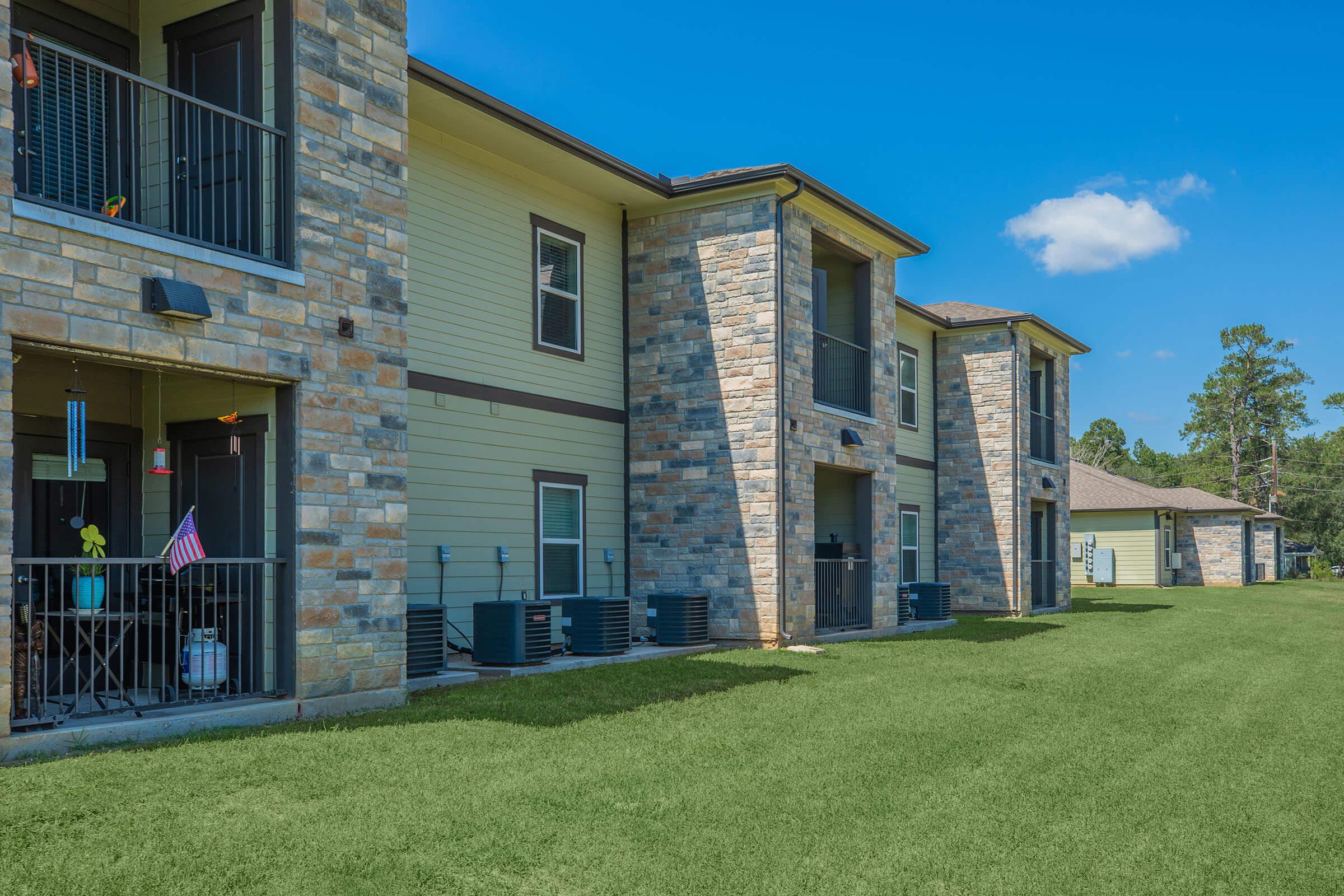 a large brick building with grass in front of a house