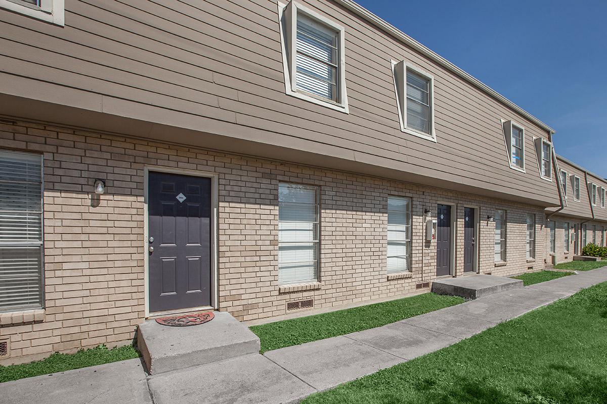 a large brick building with grass in front of a house