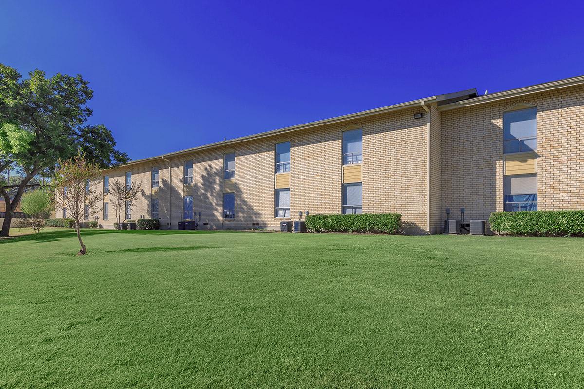 a large brick building with a grassy field with Arlington Court in the background