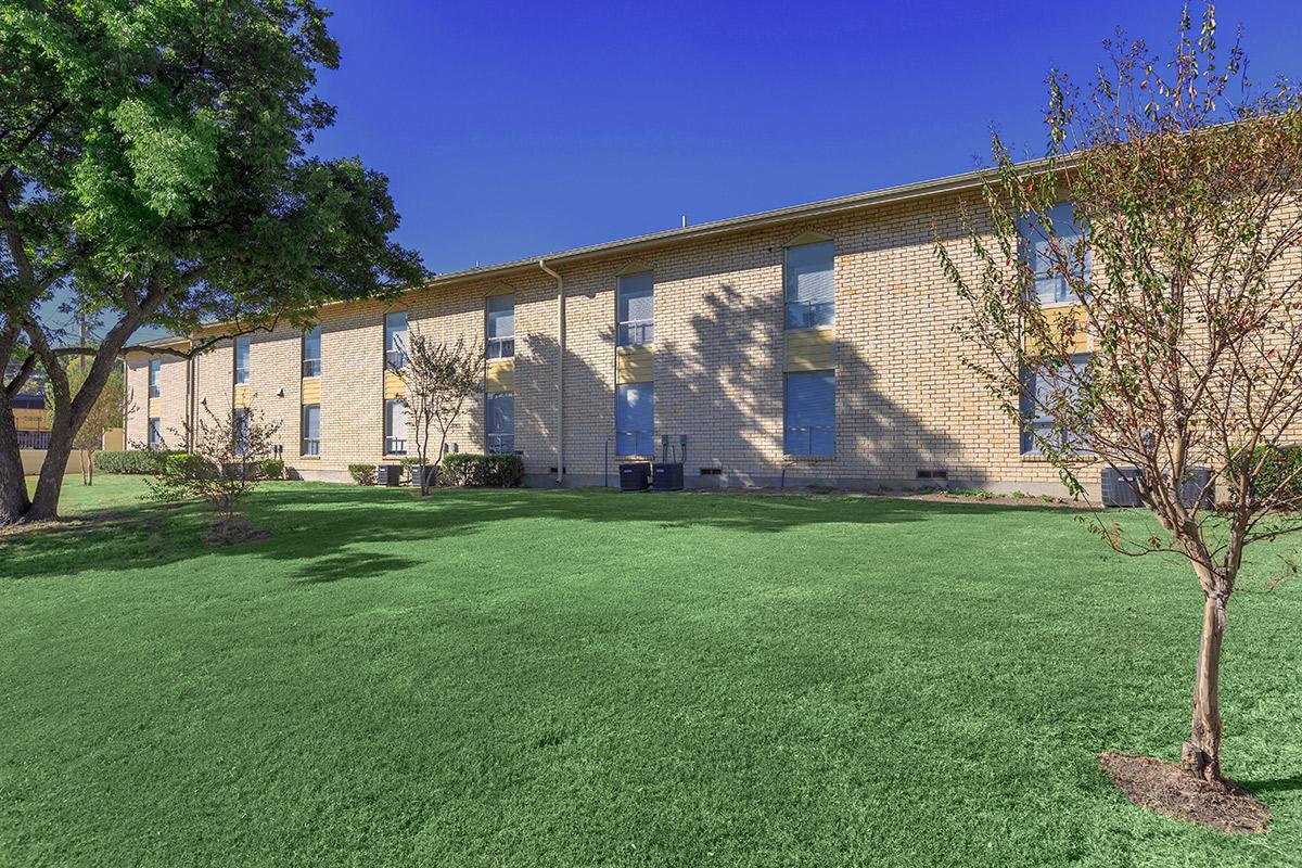 a large brick building with a grassy field