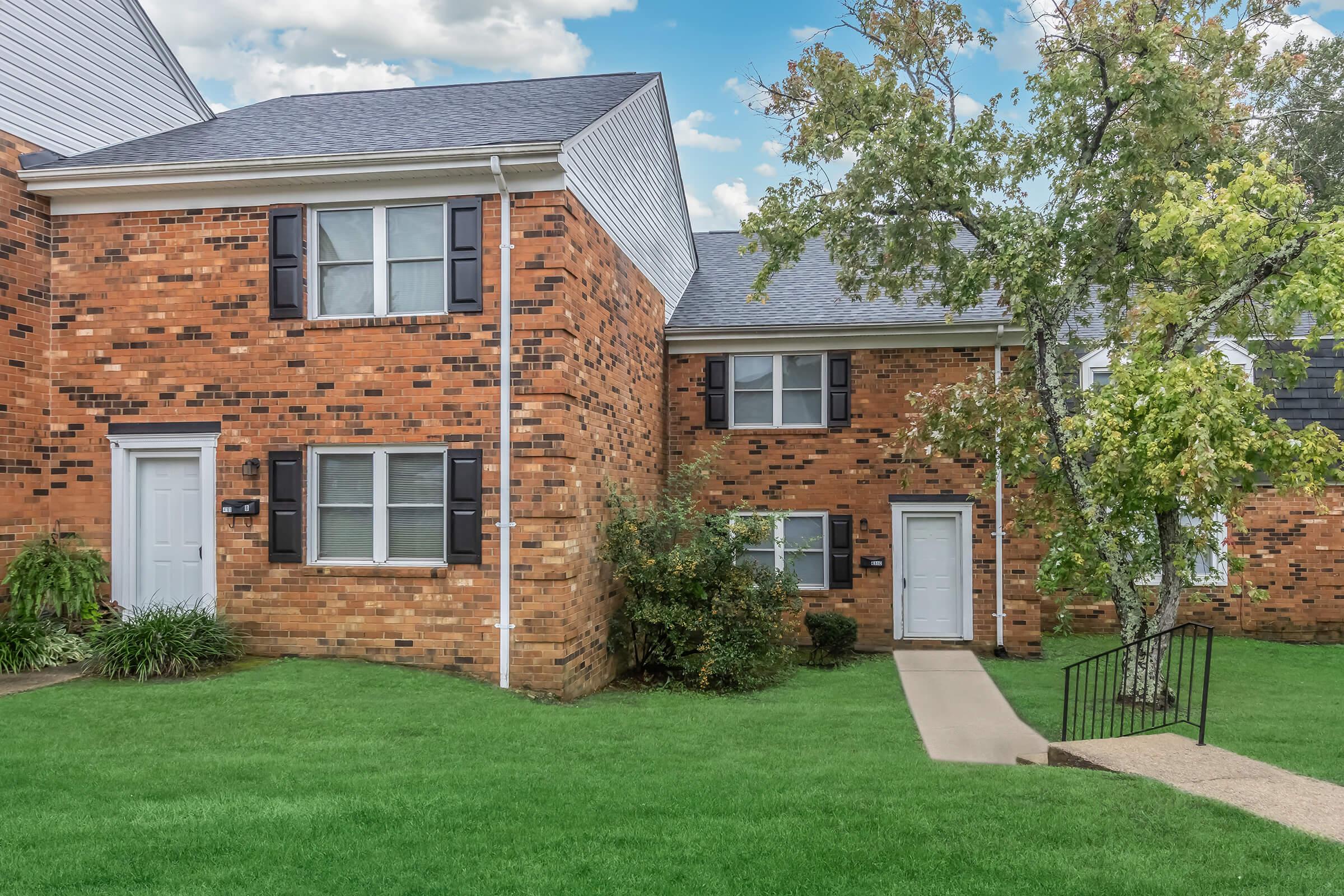 a house with a lawn in front of a brick building