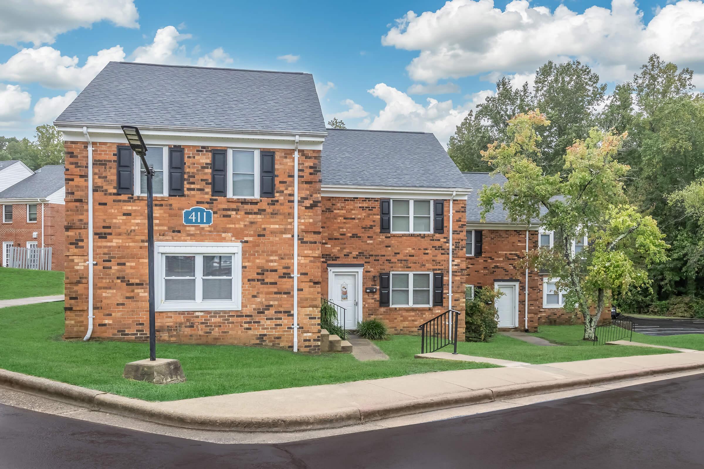 a large brick building with grass in front of a house