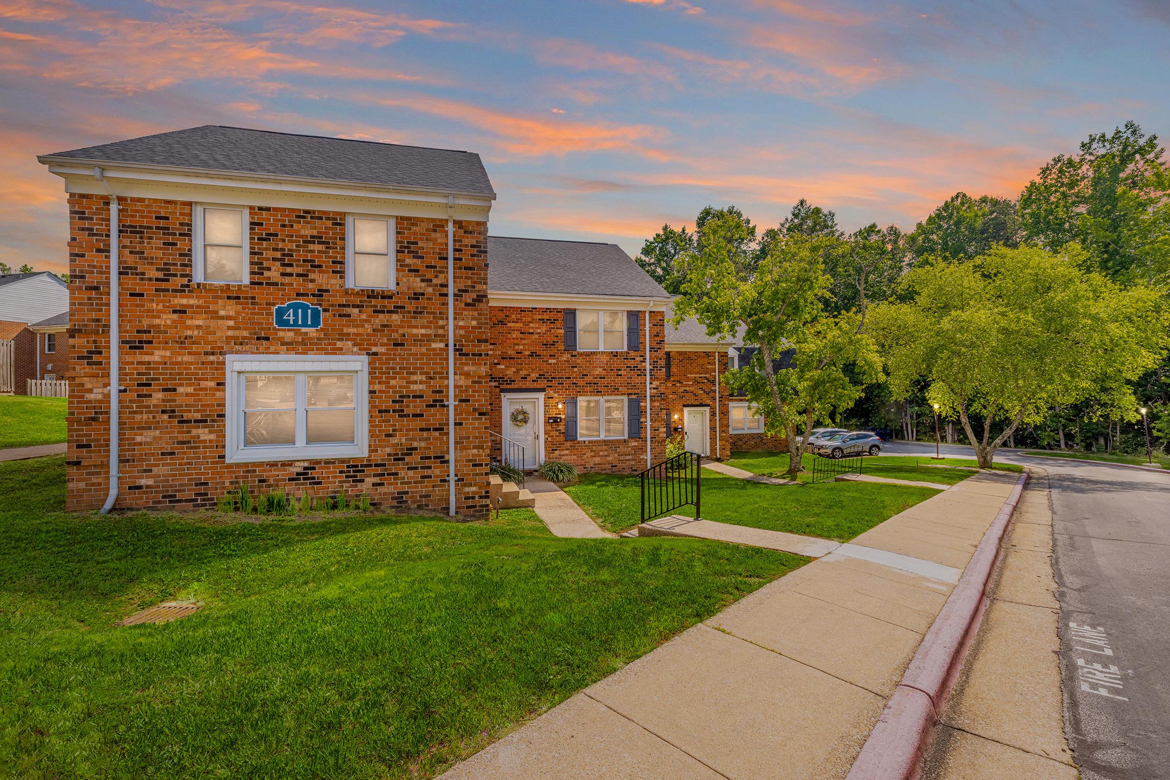 a large brick building with grass in front of a house