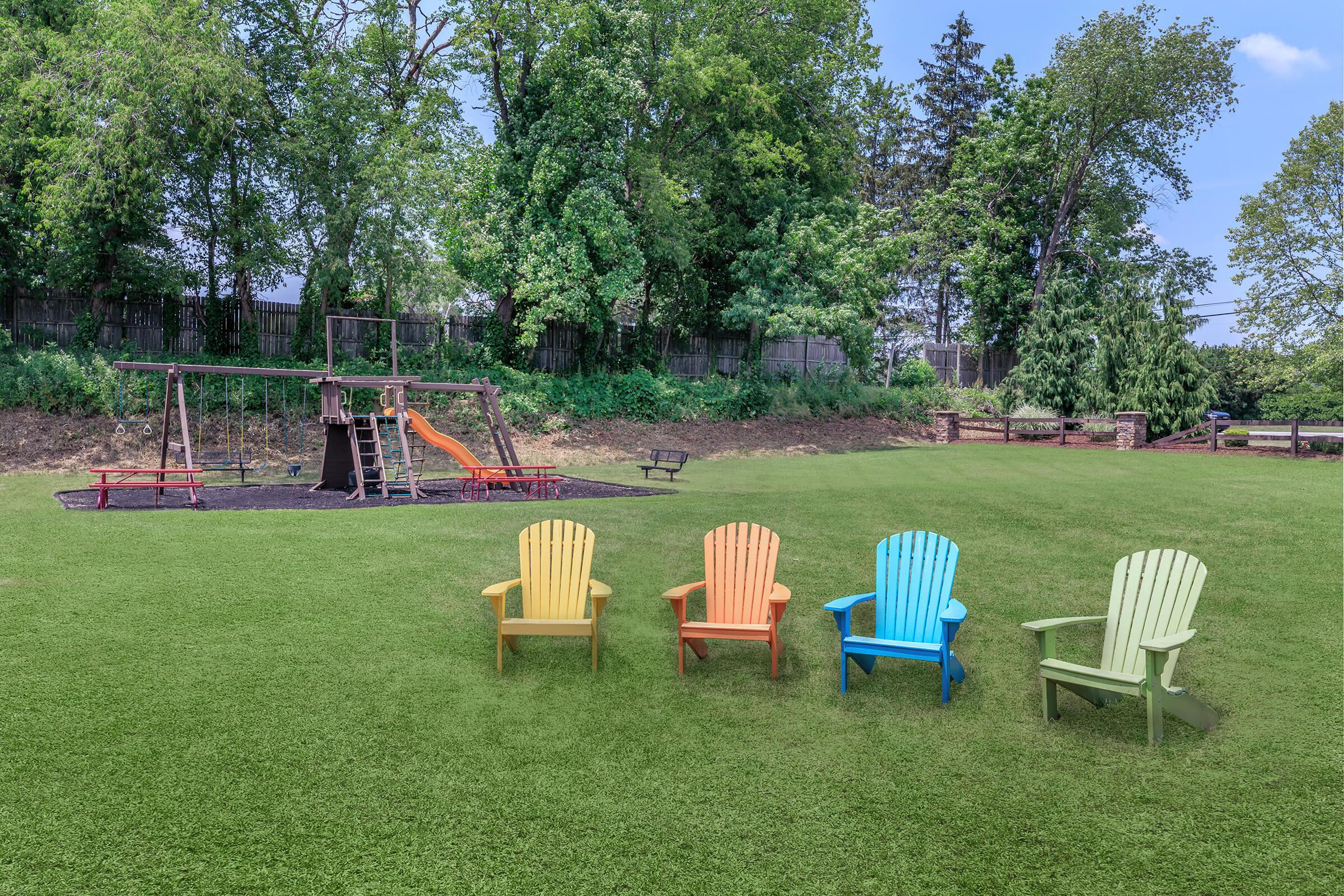 a couple of lawn chairs sitting on top of a grass covered field