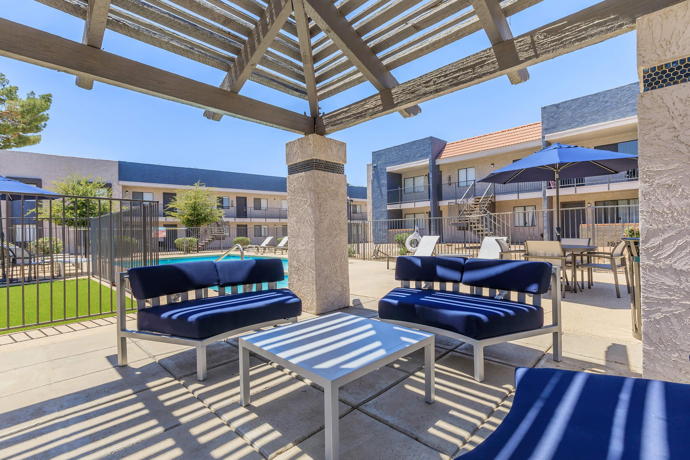 Shaded outdoor lounge area with blue couches and a table