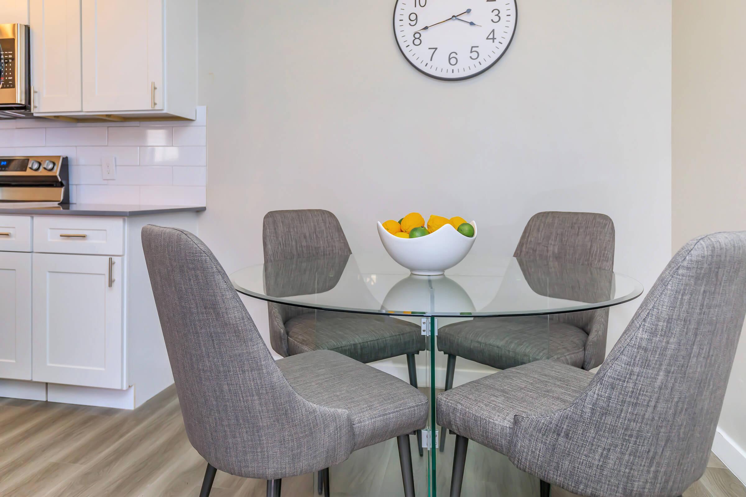 Dining room area with round glass table and grey chairs