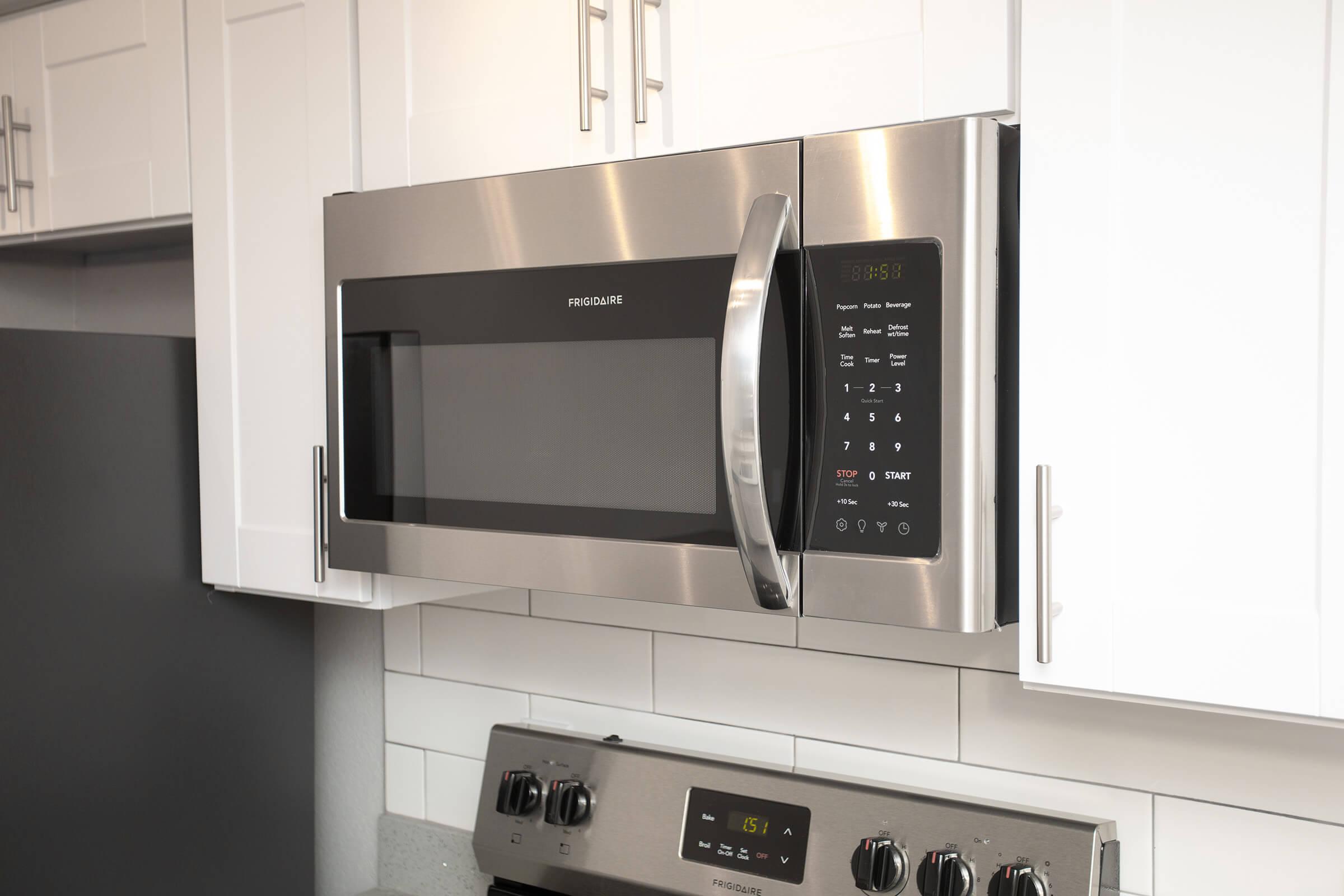 Close up of stainless steel microwave and white kitchen cabinets