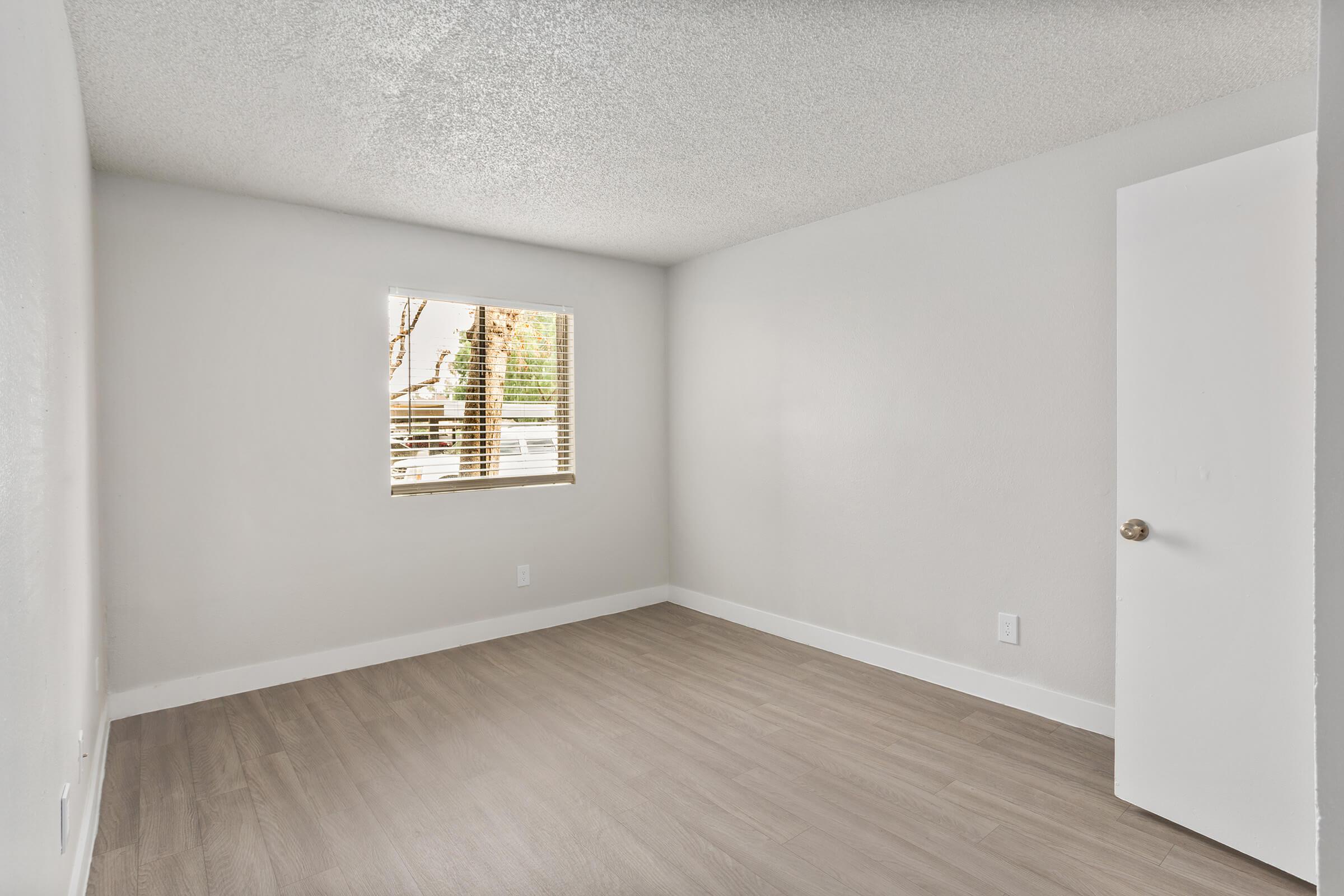 Large empty bedroom with plank flooring and a small window
