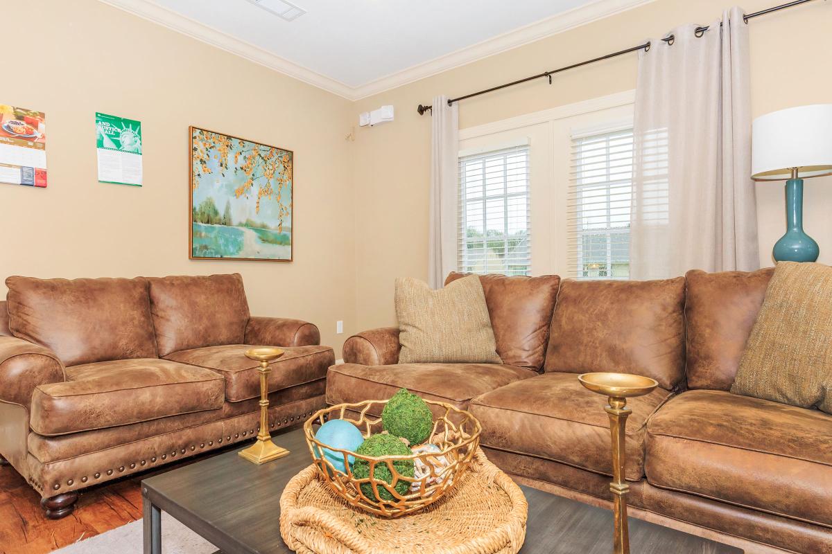 a brown leather couch in a living room filled with furniture and a fireplace