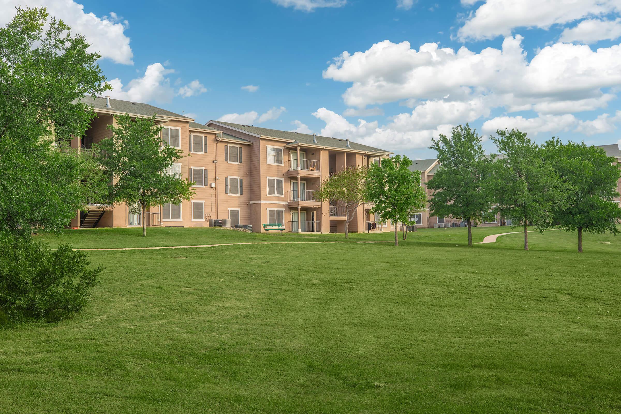 a large brick building with a grassy field
